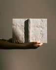 Person holding a textured book against a plain background