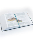 Open book on a white surface with architectural illustrations and text
