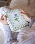 Person holding a decorative book with floral design