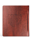Brown leather notebook with engraved text on a white background