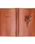 Brown leather notebook with floral embossing on a white background