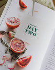 Open book with a page showing a blood orange and thyme, labeled 'Week One Day Two'.