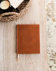 Brown leather notebook with embossed design on a wooden surface