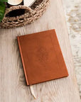 Brown leather notebook with embossed design on a wooden surface
