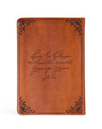 Brown leather notebook with engraved text on a white background