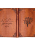 Brown leather notebook with floral design and text on a white background
