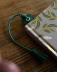 Green cord bookmark on a notebook with leaf pattern on a wooden surface