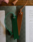 Two leather bookmarks, one green and one brown, on a book with text.