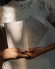 Person holding two patterned books with a lace garment in the background