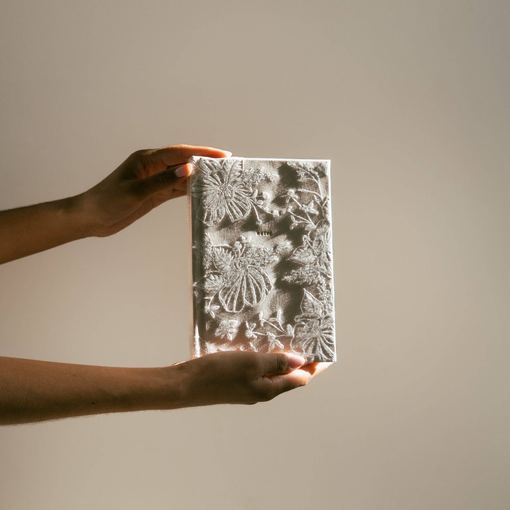 Person holding a textured rectangular object against a plain background