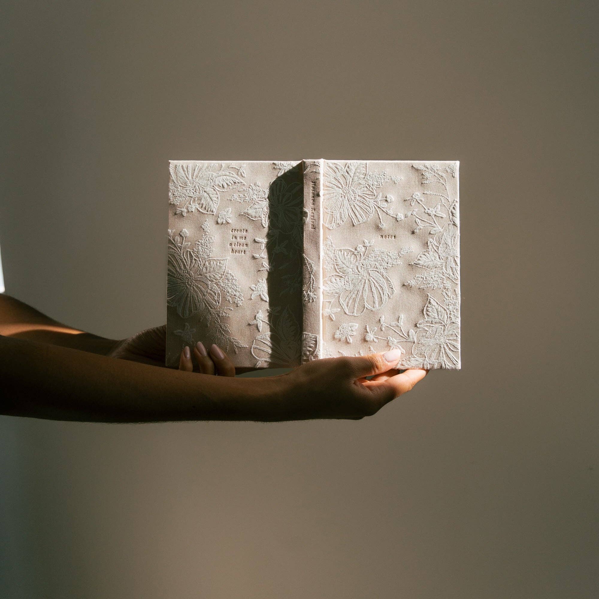 Person holding a textured book against a plain background
