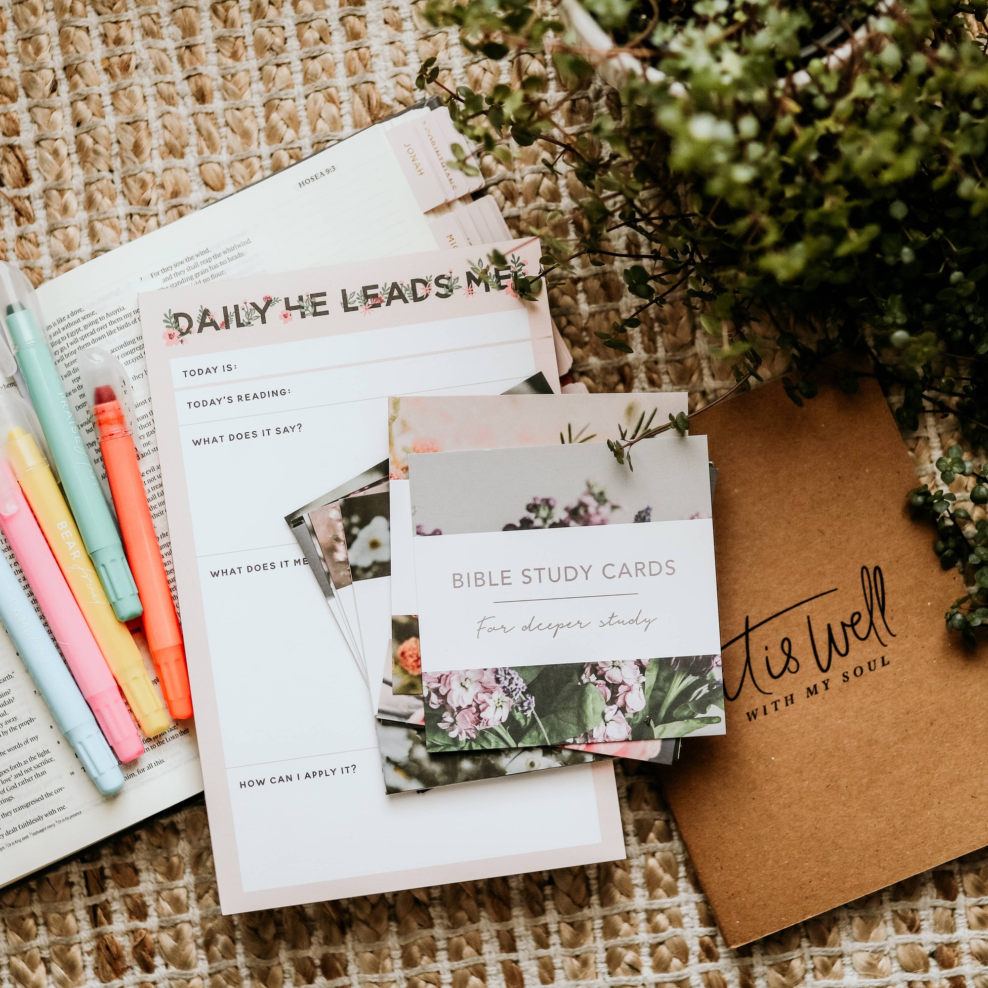 Bible study materials including cards and a notebook on a textured surface with plants.