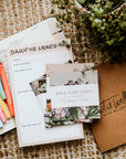 Bible study materials including cards and a notebook on a textured surface with plants.