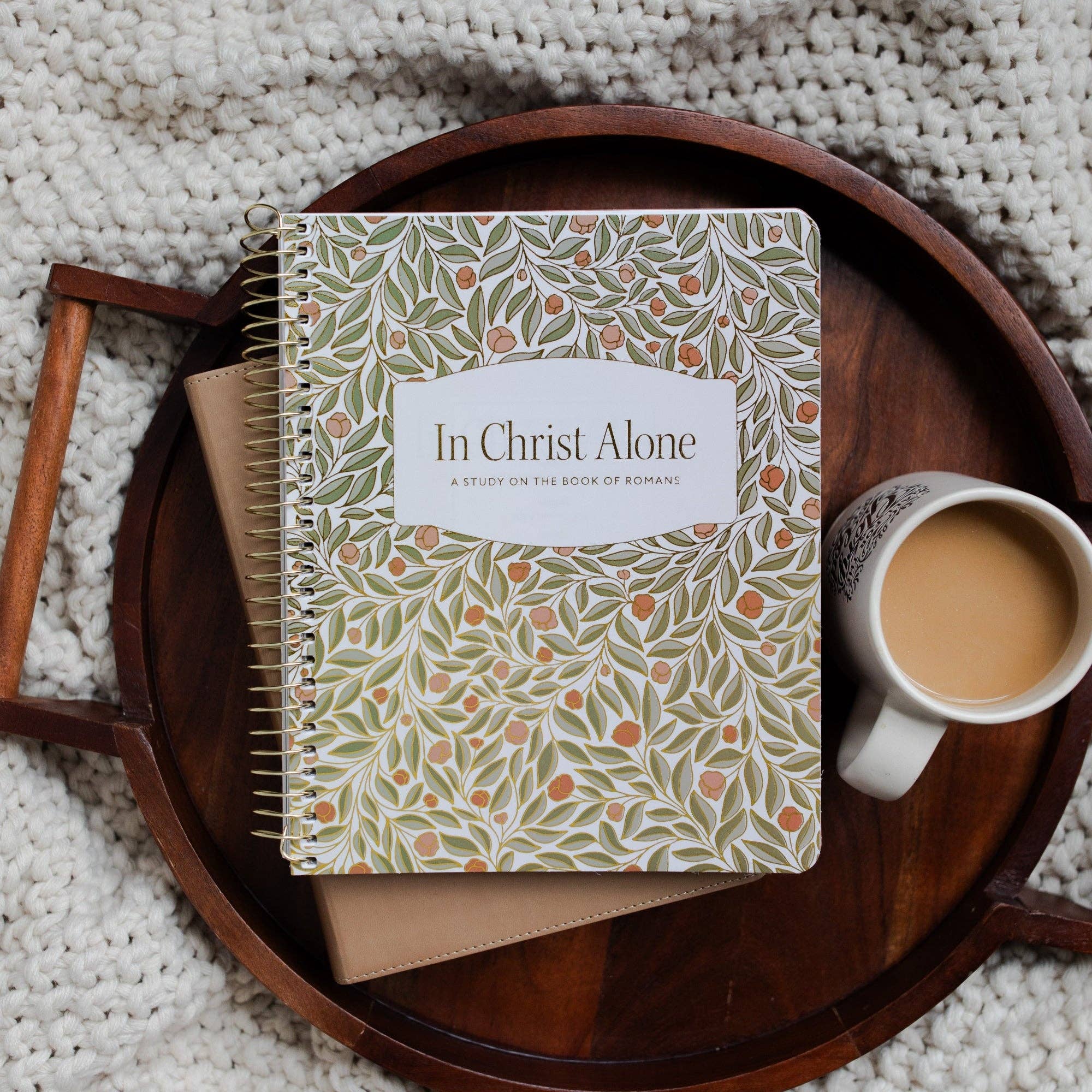 Notebook titled 'In Christ Alone' on a wooden tray with a cup of coffee