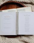Open book on a wooden tray with a textured beige background