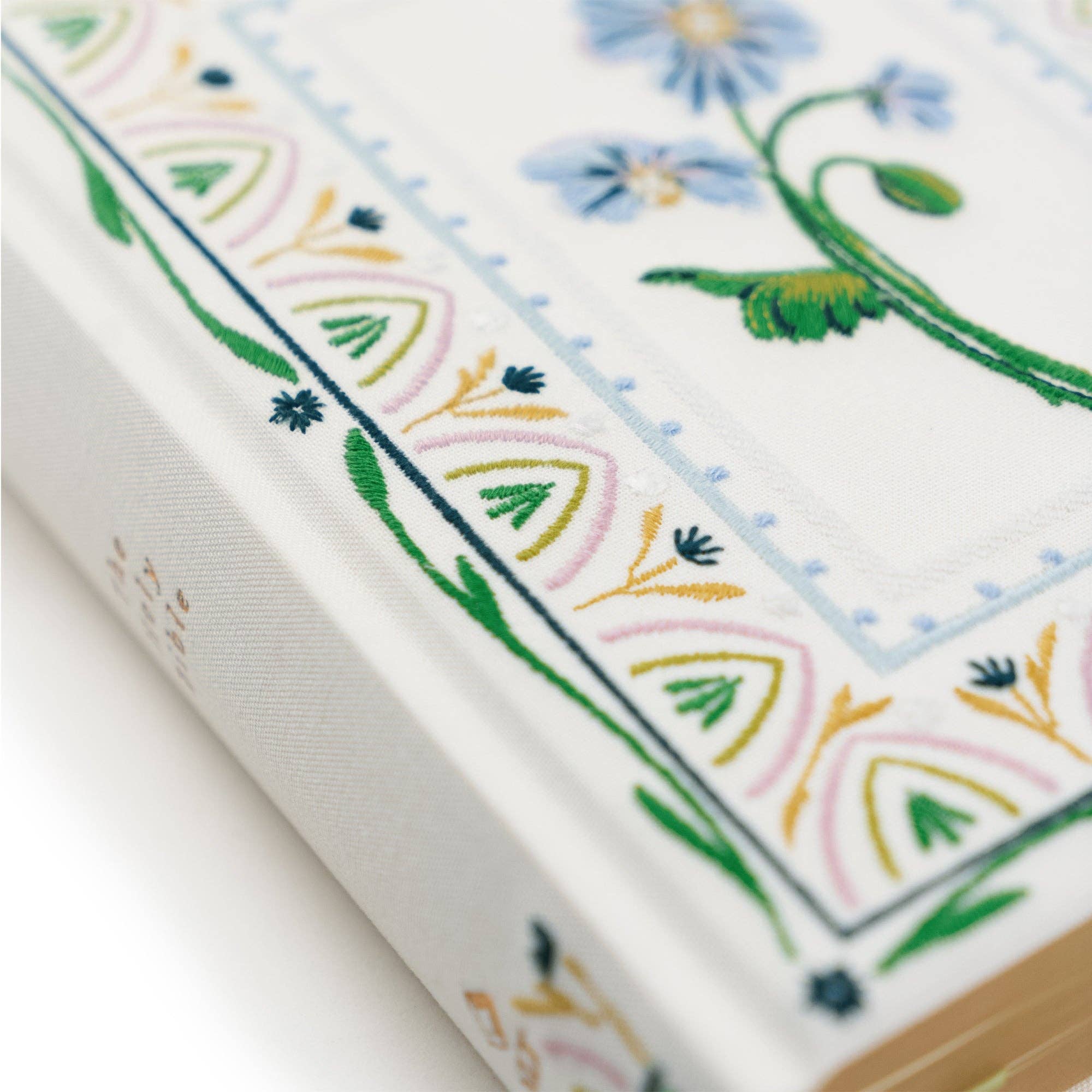 Close-up of a book with floral embroidery on a white background