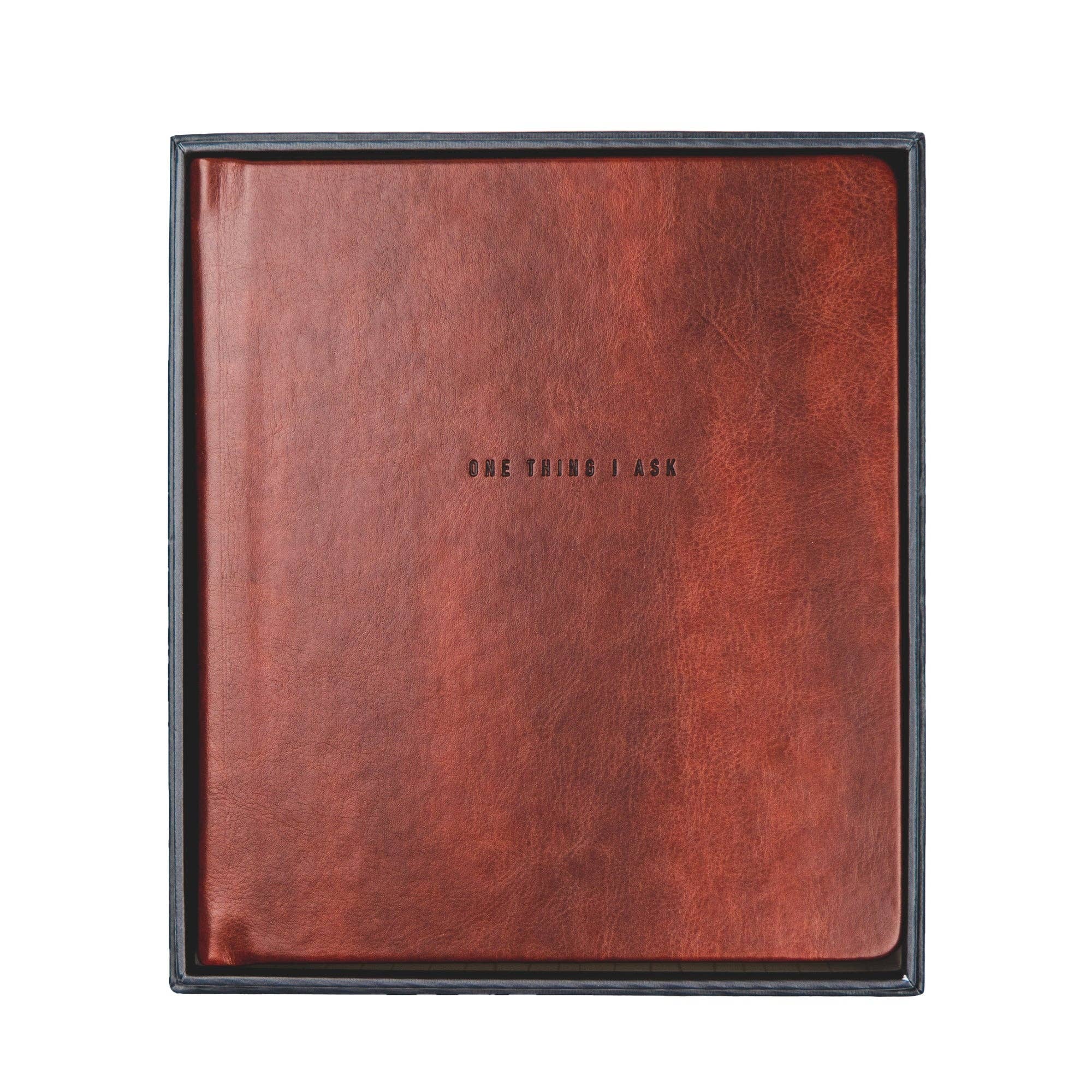 Brown leather-bound book with &#39;ONE THING I ASK&#39; embossed on a white background