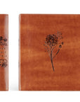 Brown leather-bound book with floral design on a white background