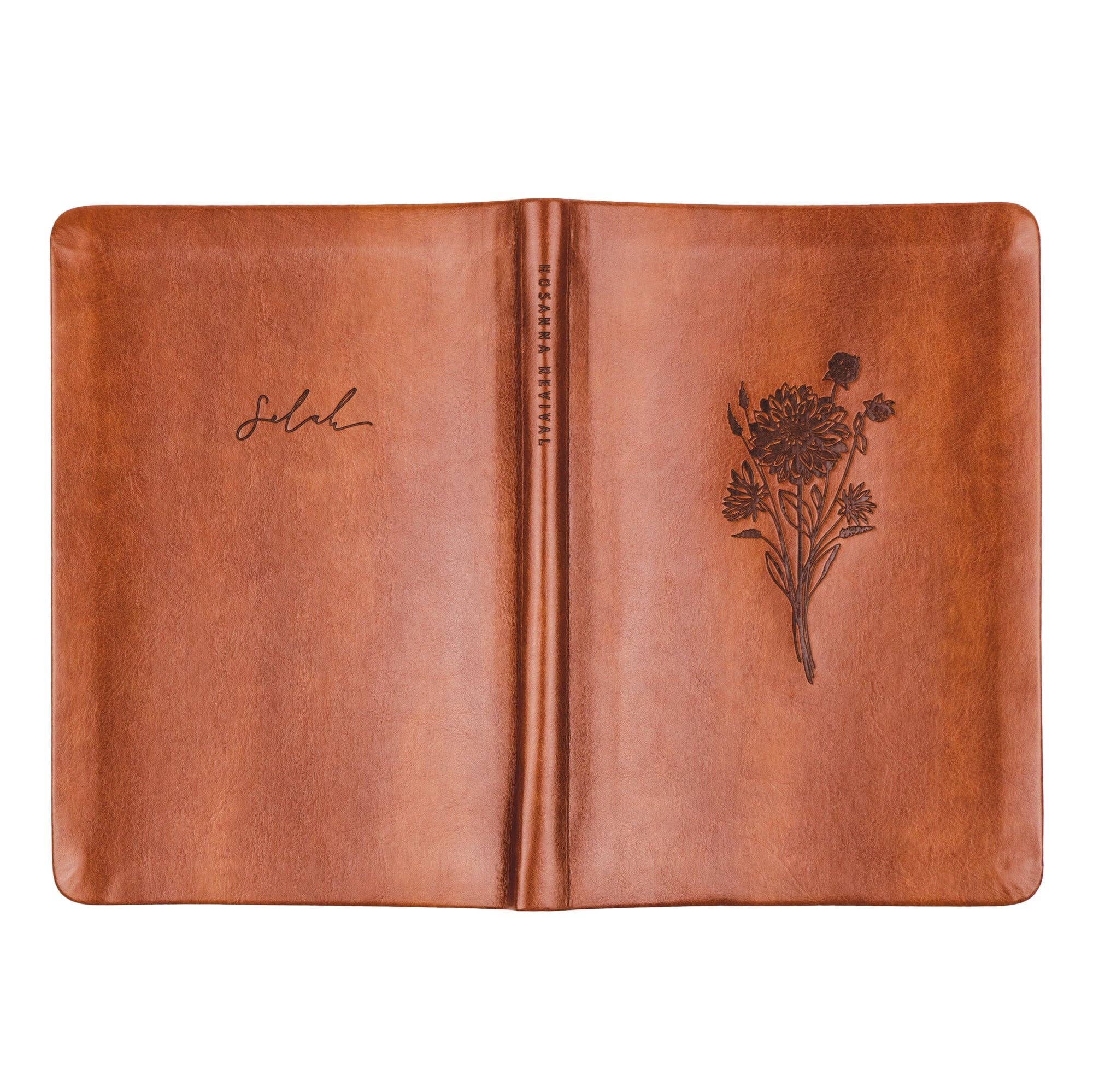 Brown leather notebook with floral embossing on a white background