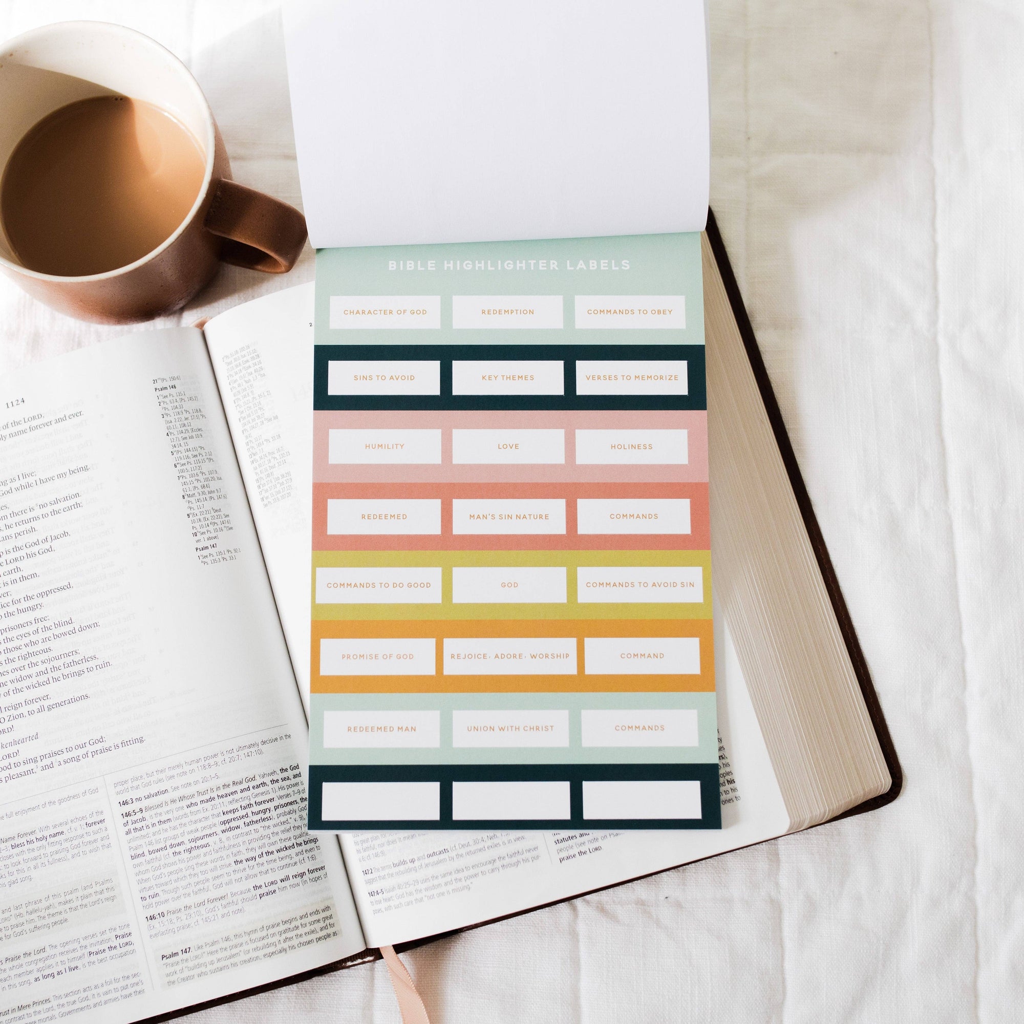 Sheet of colorful planner stickers on an open book with a cup of coffee.