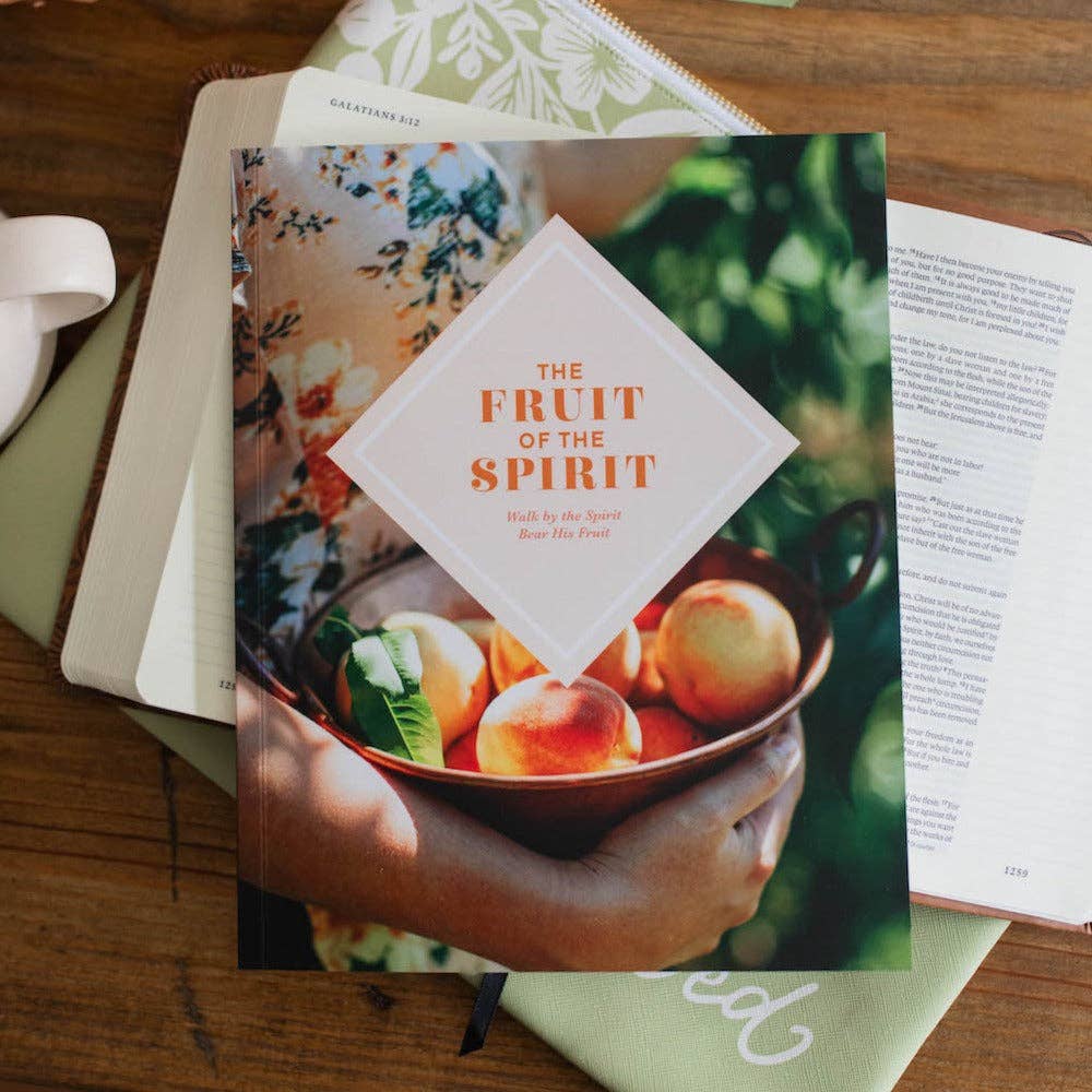 Book titled 'The Fruit of the Spirit' on a wooden surface with a floral patterned book.