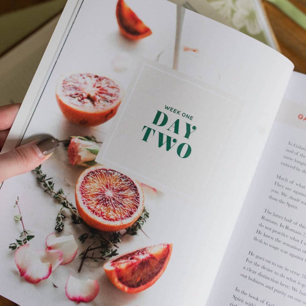 Open book with a page showing a blood orange and thyme, labeled 'Week One Day Two'.