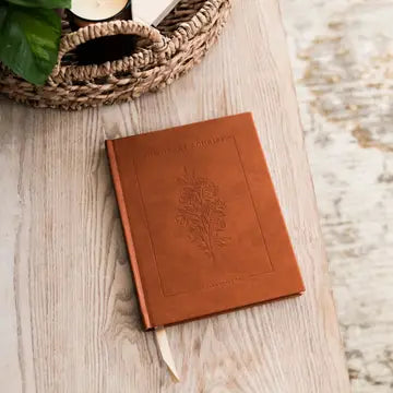 Brown leather notebook with embossed design on a wooden surface