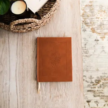 Brown leather notebook with embossed design on a wooden surface