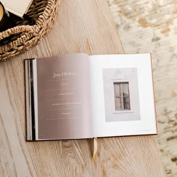 Open book on a wooden surface with text and a small image of a window.
