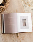 Open book on a wooden surface with text and a small image of a window.