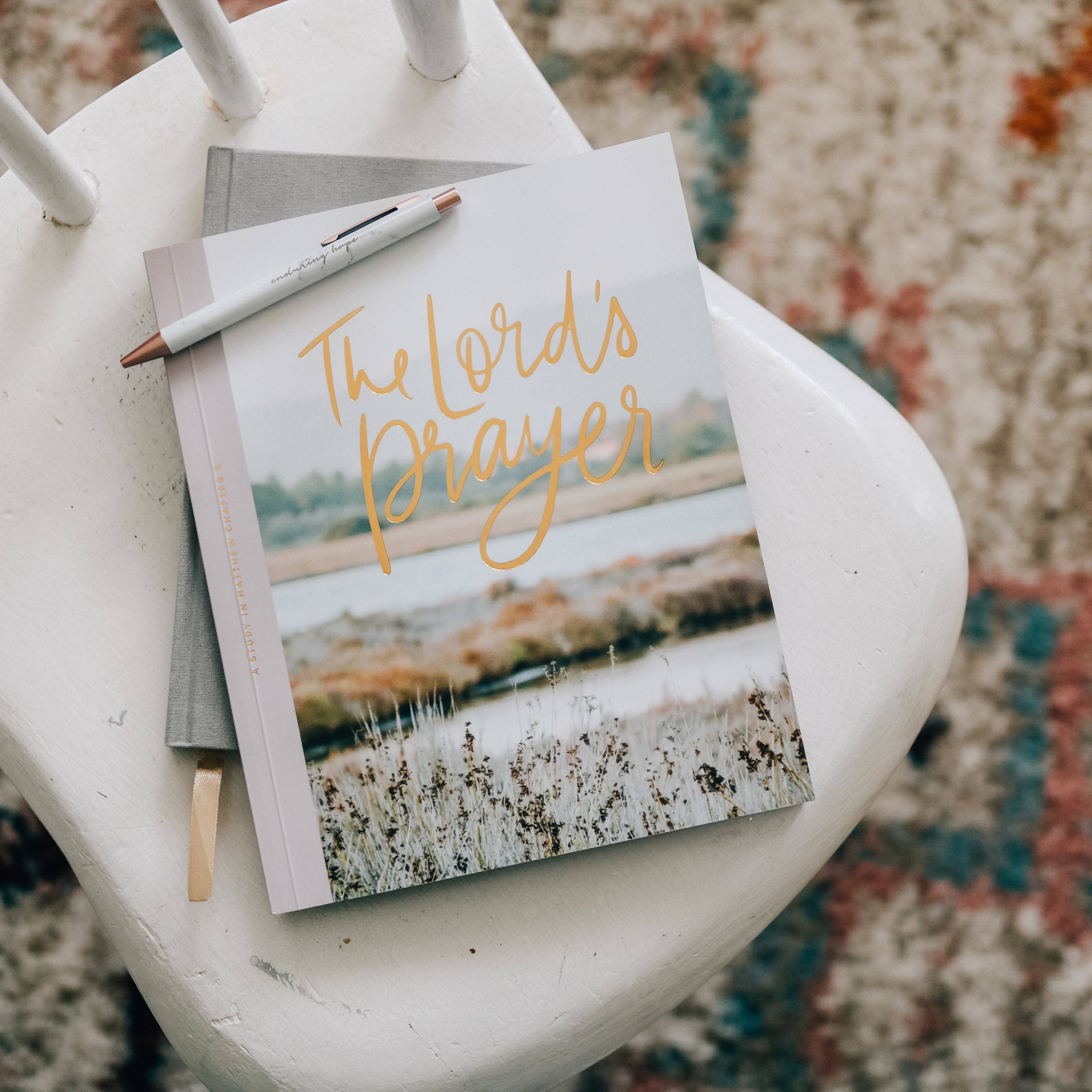 Book titled &#39;The Lord&#39;s Prayer&#39; with a pen on a white chair
