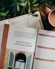 Open book with a quote on a wooden table with a cup of coffee and plant