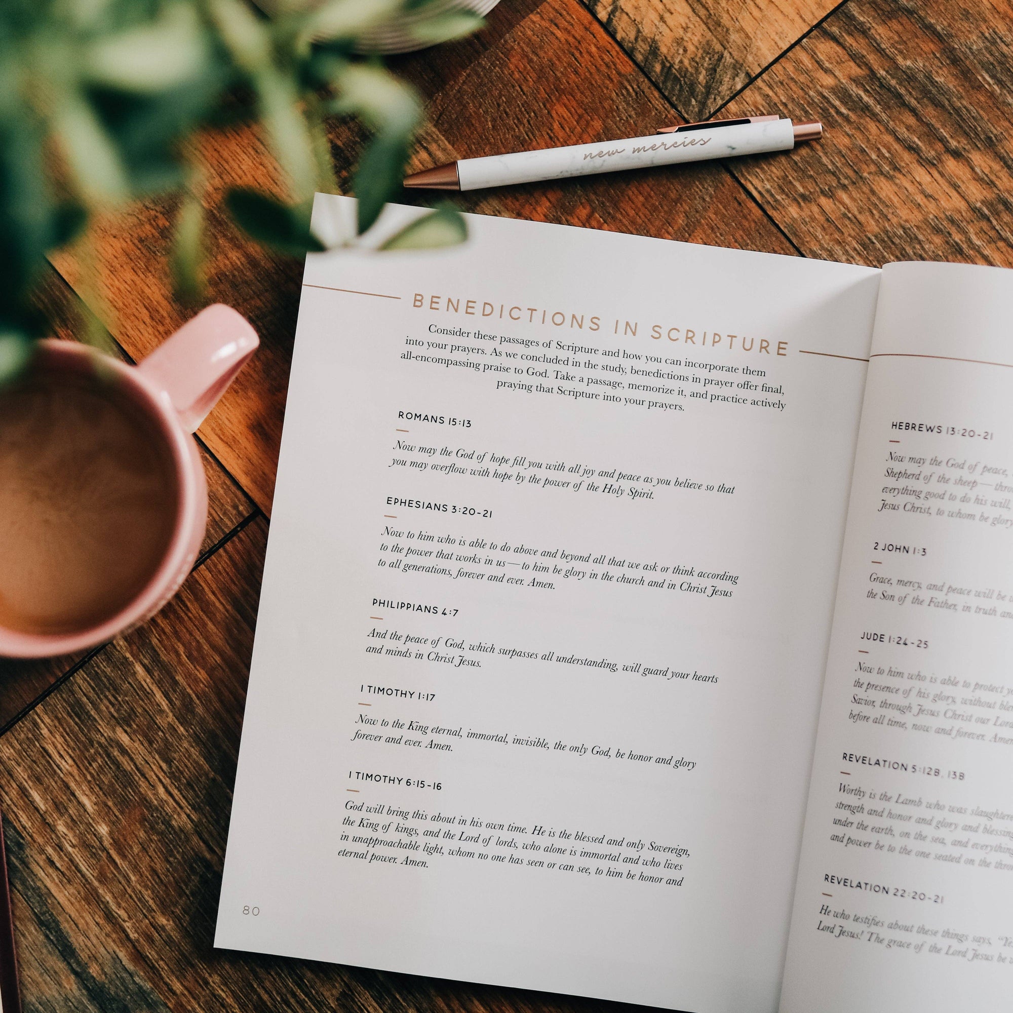 Open book on a wooden table with a pen and mug nearby