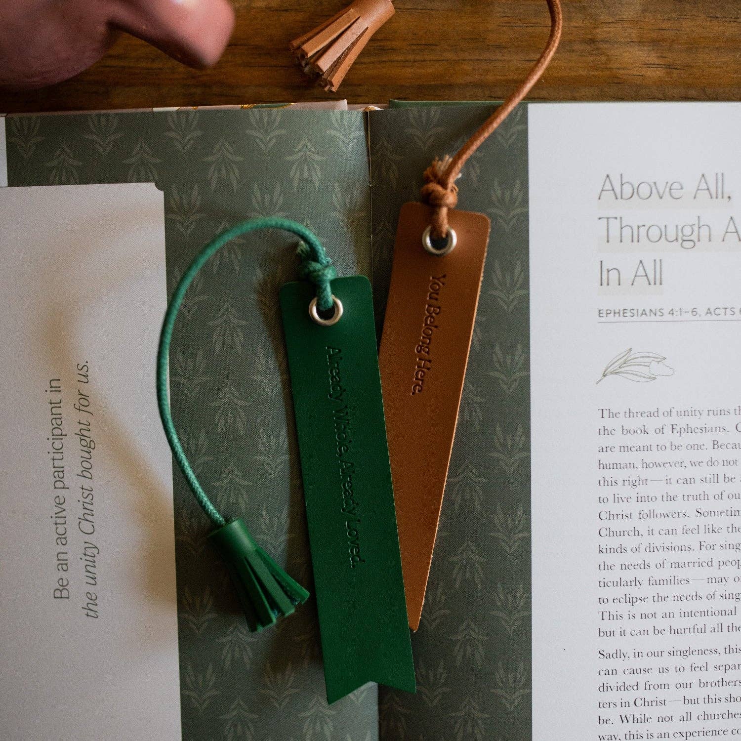 Two leather bookmarks, one green and one brown, on a book with text.